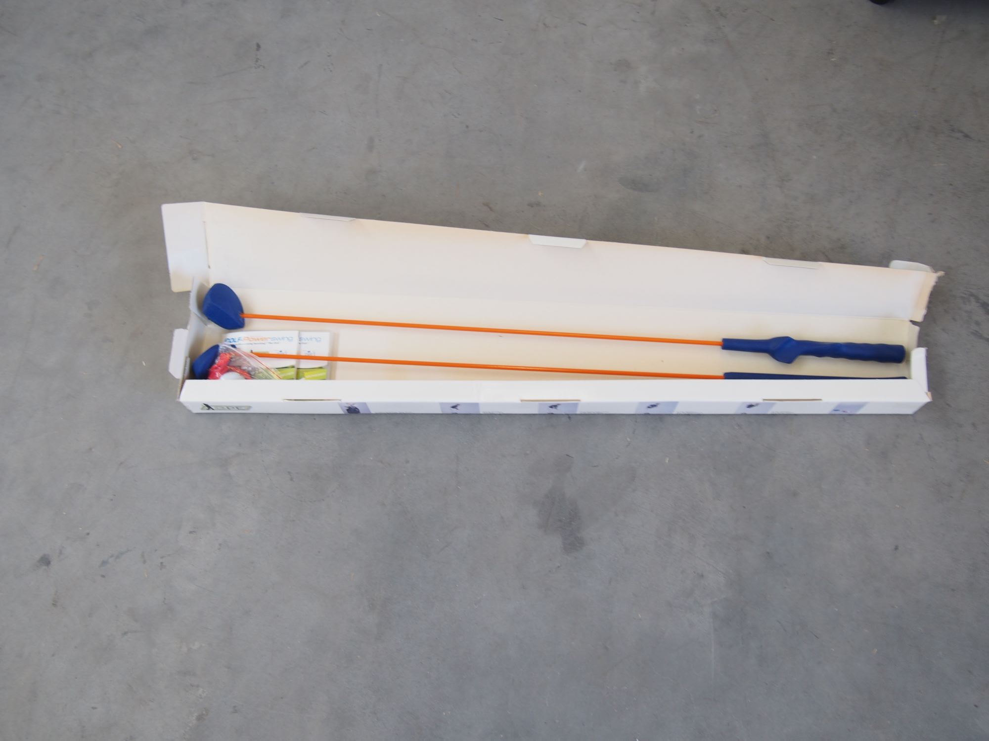 Golf Power Swing Trainingsgerät mit orangefarbenen Schwungstäben in der Verpackung