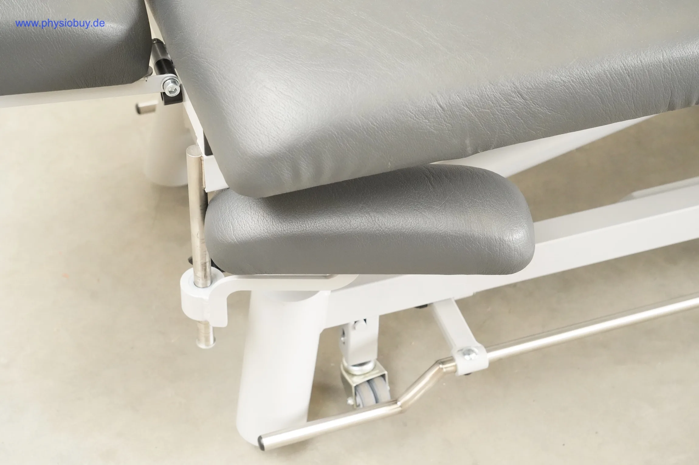 Pino XPert+ Therapieliege, Detail mit grauem Polster, seitlicher Armstütze, weißem Rahmen und Fußbügel aus Metall