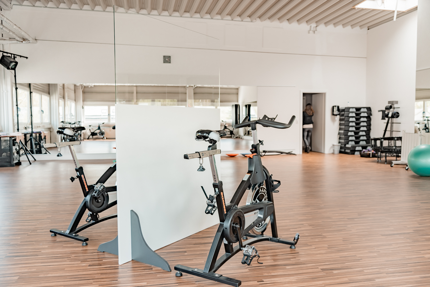Trennwand Standard mit transparentem Oberteil steht zwischen Indoor-Cycles im Fitnessstudio