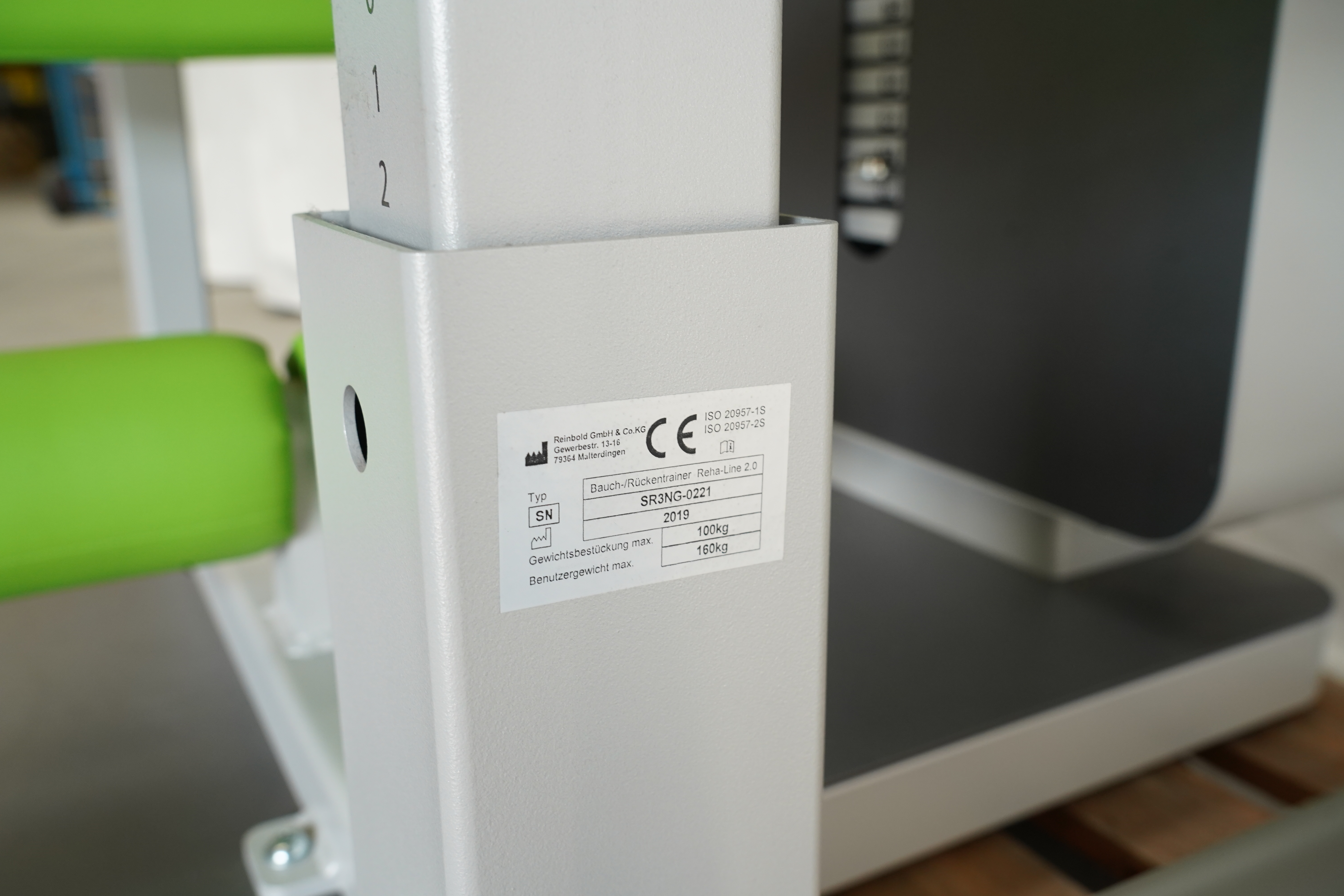 Typenschild mit CE-Zeichen an der Säule des SVG RehaLine 2.0 KG-Gerätesatzes, daneben grüne Polsterrollen