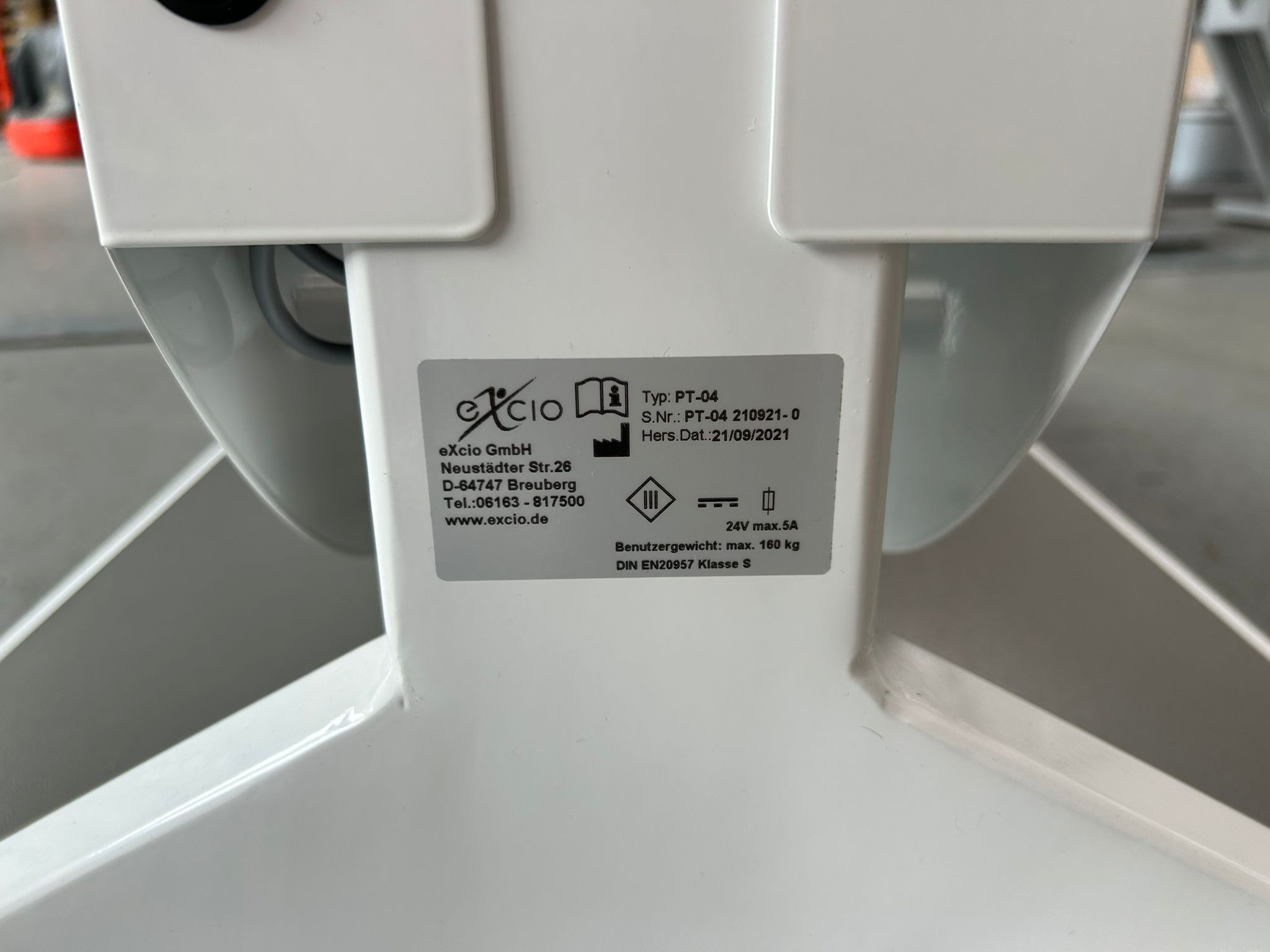 Typenschild des Excio Beckenbodentrainers mit Hersteller- und Seriennummerangaben