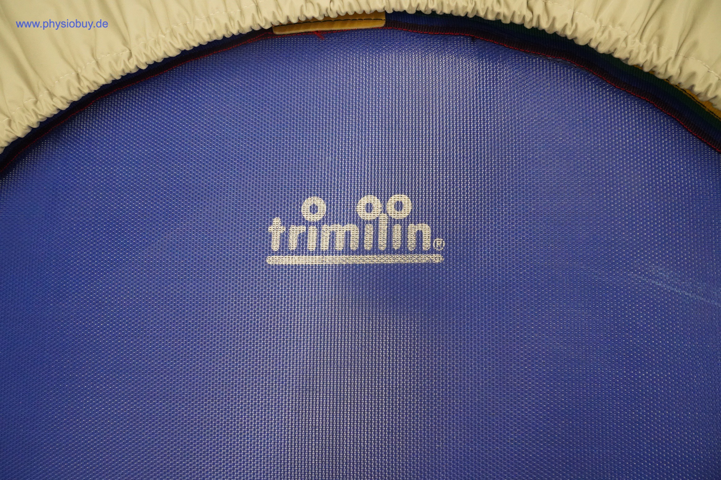Trimilin Trampolin, Detail der blauen Sprungmatte mit weißem Trimilin-Logo, oben der cremefarbene Rand der Abdeckung