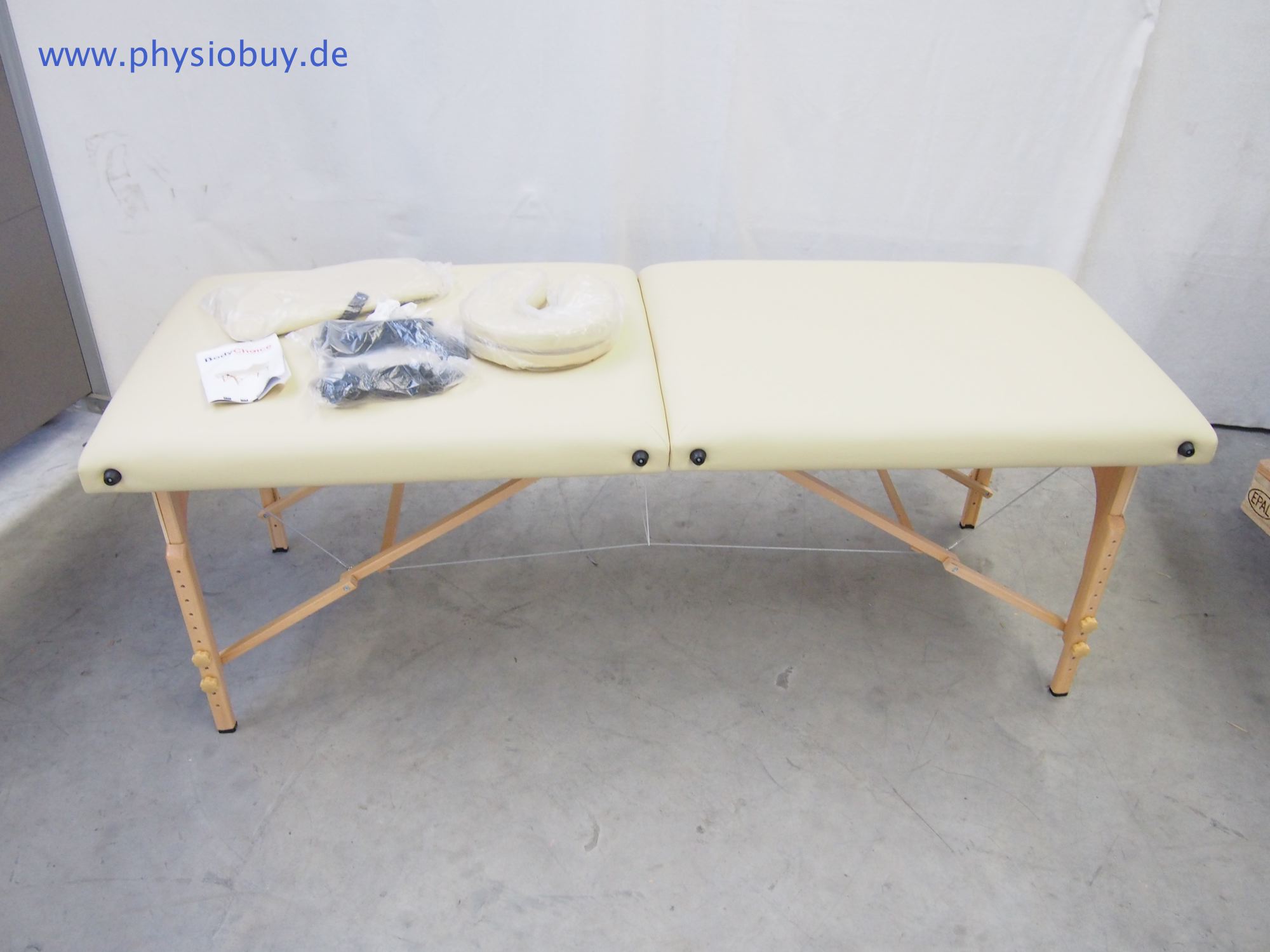 Tragbare Koffermassageliege aus Holz mit cremefarbenem Polster und Zubehör