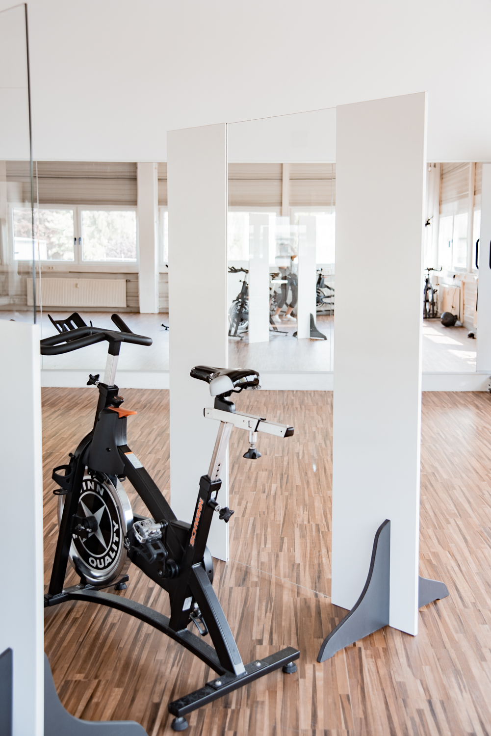 Trennwände Exclusive mit Glasstreifen stehen zwischen Indoor-Cycles im Fitnessstudio