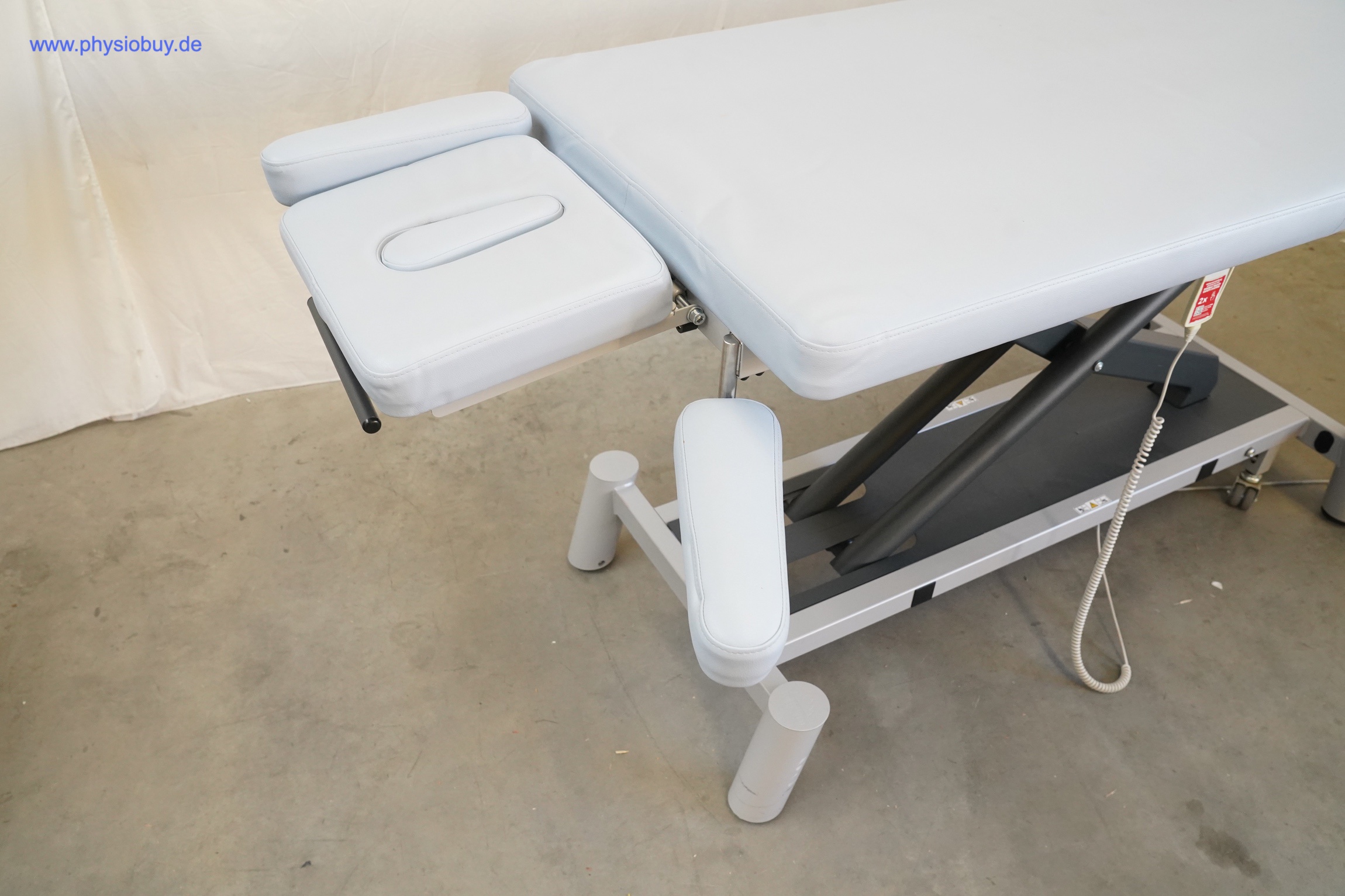 PINO XPert+ Therapieliege schräg von vorn mit Kopfteil, Gesichtsöffnung, Scherenhubgestell und Fußbügel an der Seite