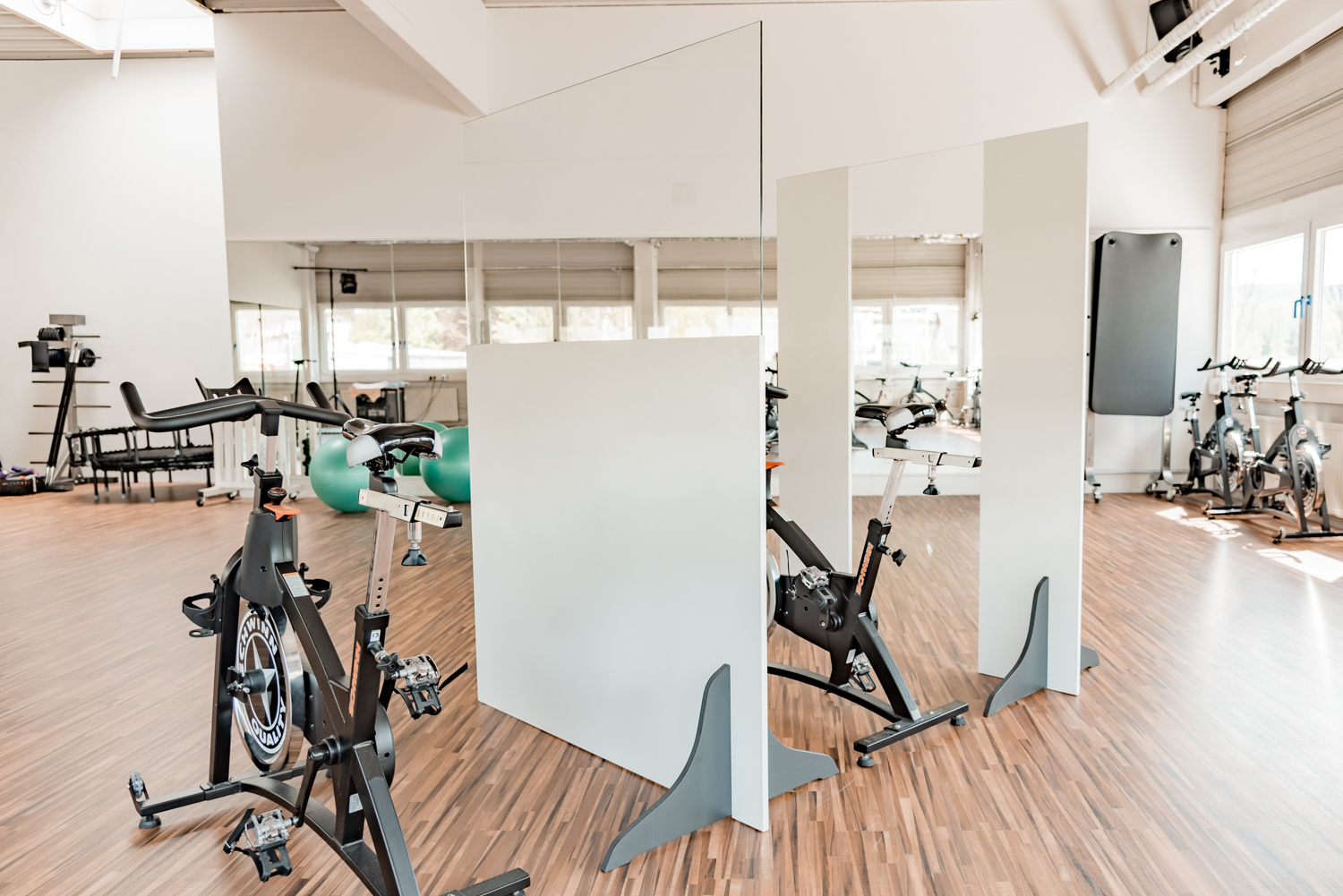 Mehrere Trennwände Standard stehen versetzt zwischen Indoor-Cycles im Fitnessstudio