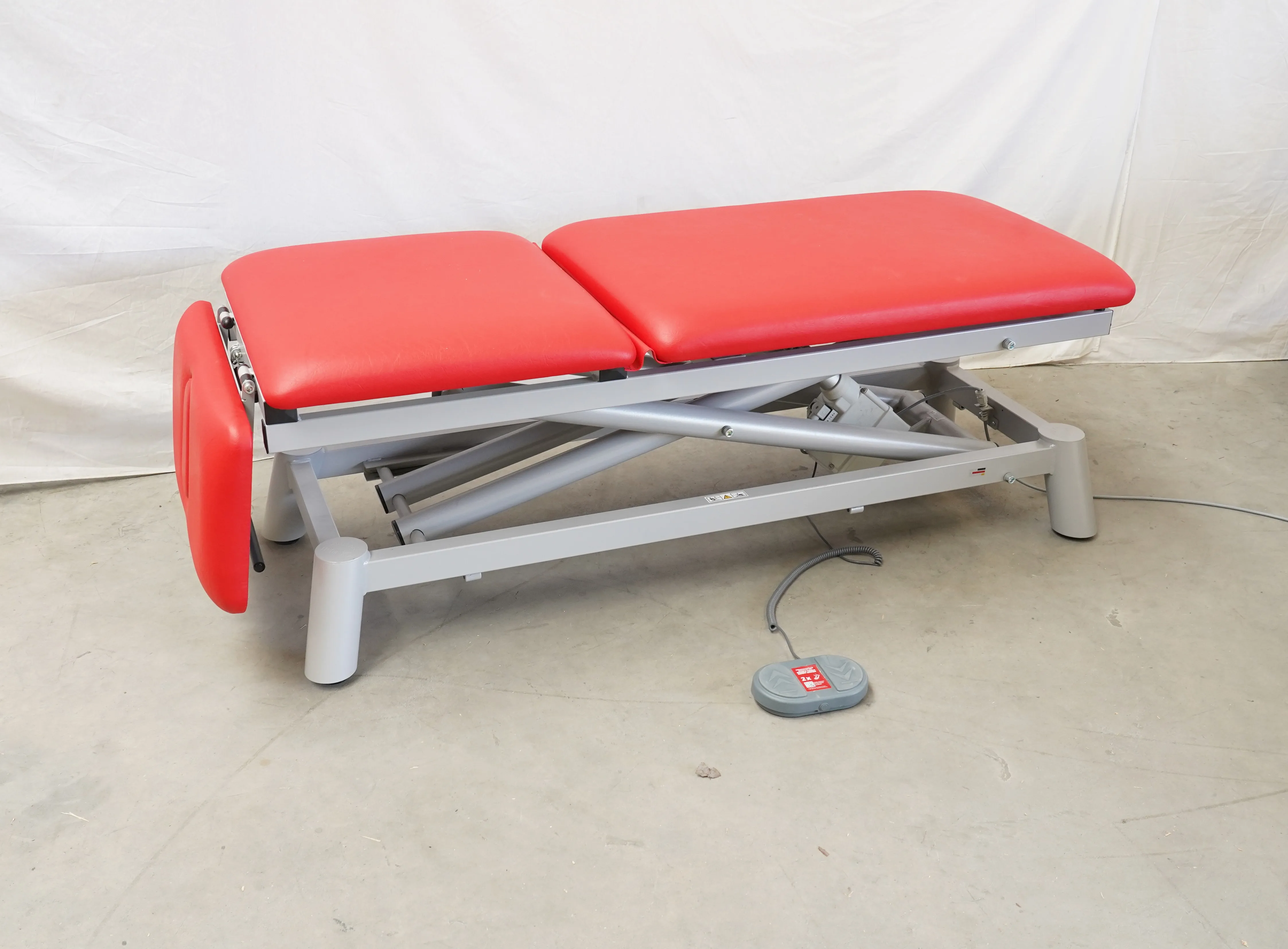 Therapieliege Pino PinoPro elektr. mit rotem Polster, auf Palette, Seitenansicht
