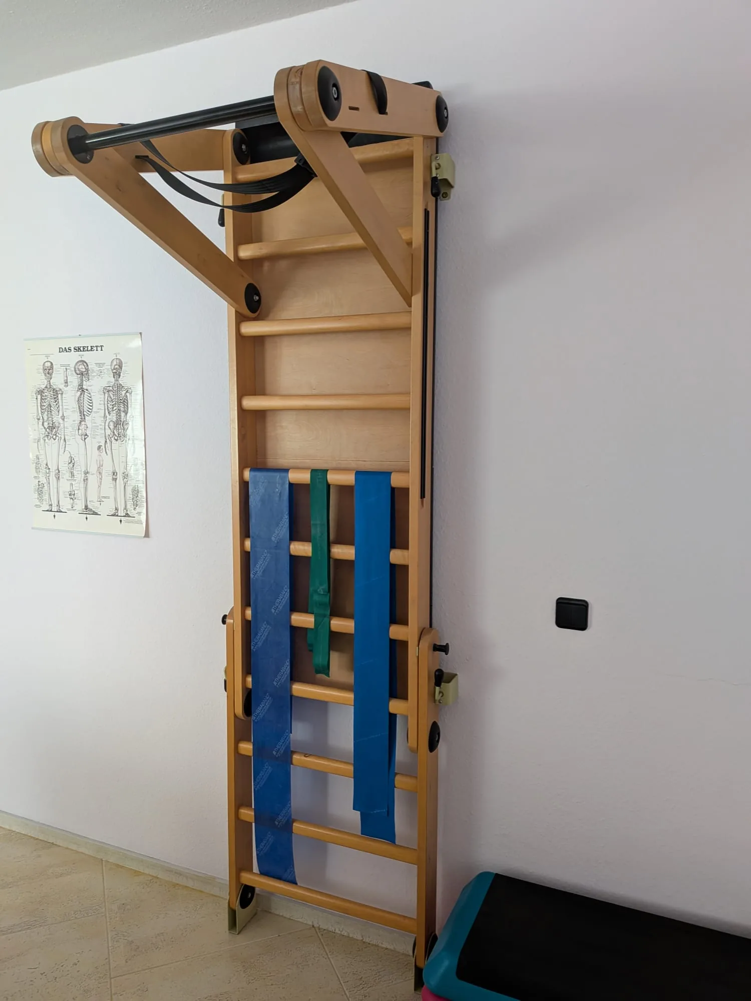 Sprossenwand KundoSet an der Wand montiert mit farbigen Zugbändern im Behandlungsraum