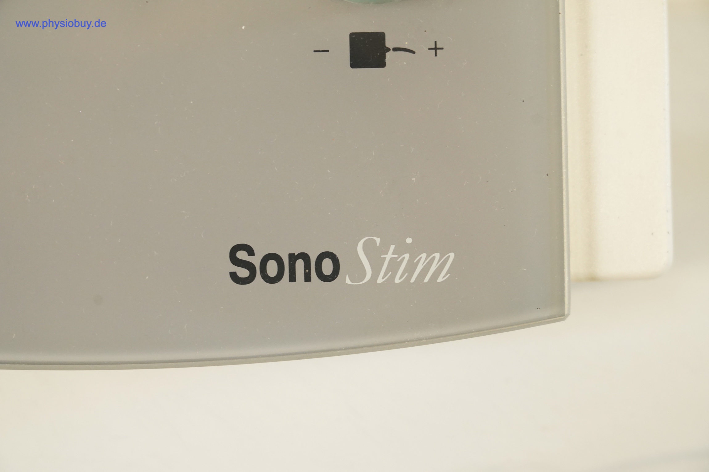 Zimmer SonoStim, Nahaufnahme des Schriftzugs auf der grauen Frontblende, darüber ein Regler mit Minus- und Plus-Symbol