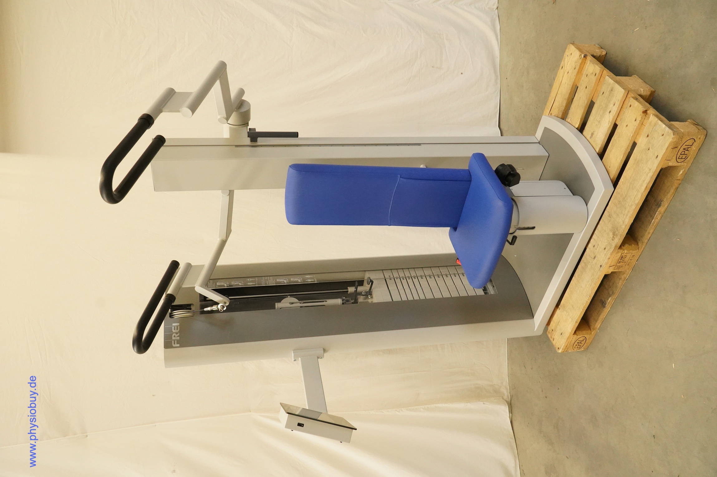 FREI Genius ECO Kraftgerät mit blauem Sitz, Griffen und Gewichtsblock, schräg von vorn auf einer Palette