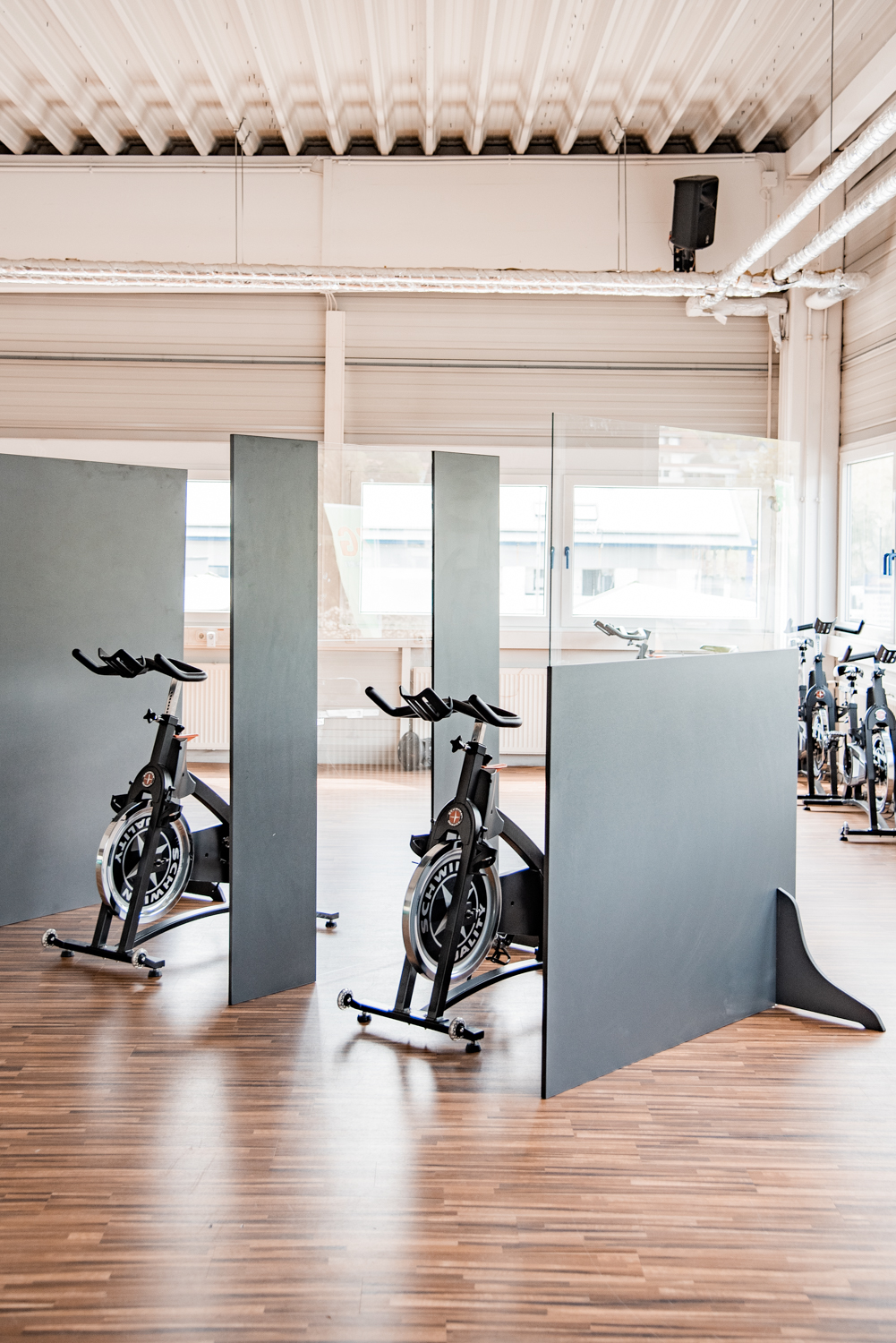 Zwei Trennwände Standard stehen zwischen Indoor-Cycles unter offener Dachkonstruktion