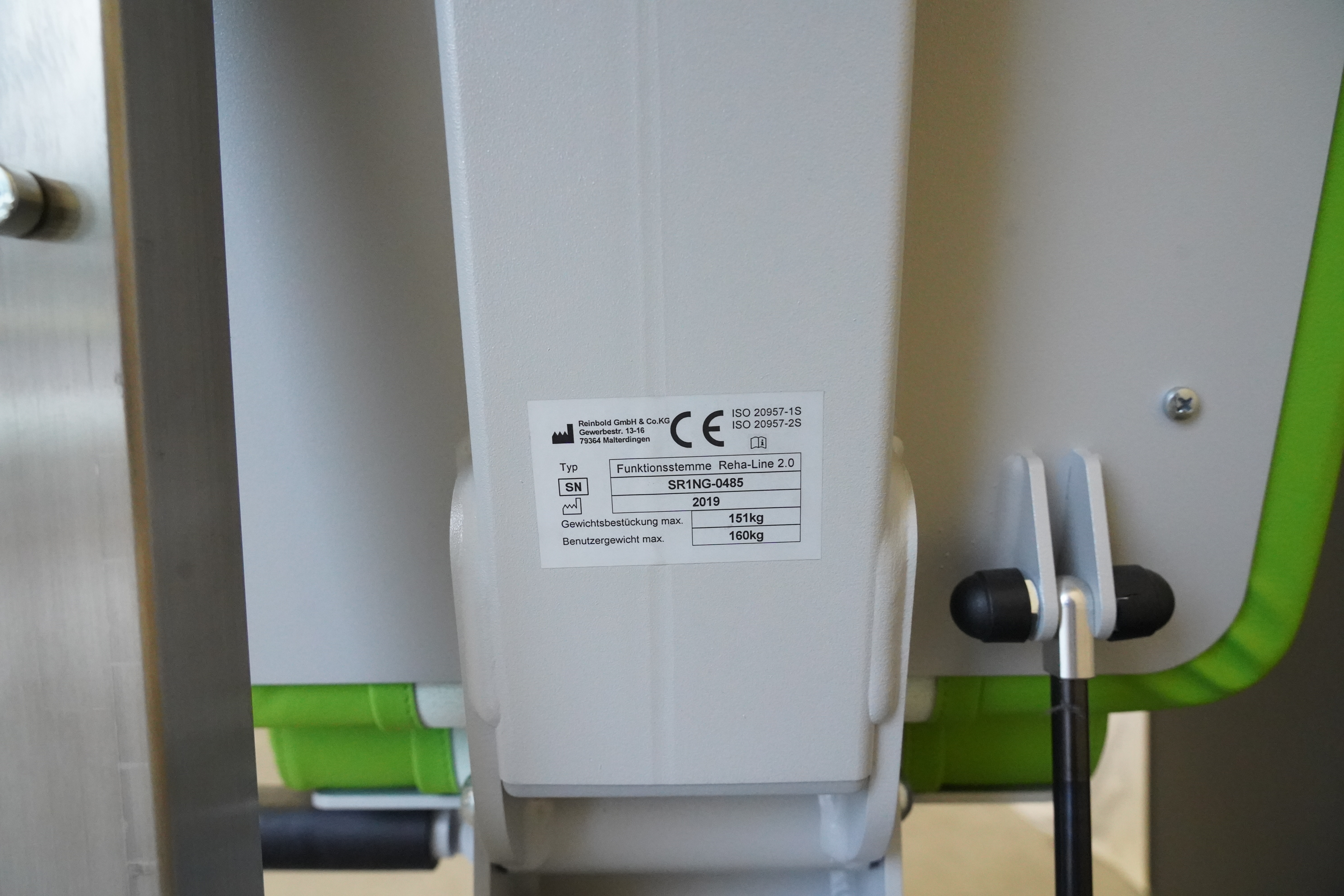 SVG RehaLine 2.0 KG-Gerätesatz: Typenschild mit CE-Kennzeichen an weißer Säule, daneben grüne Polsterkante
