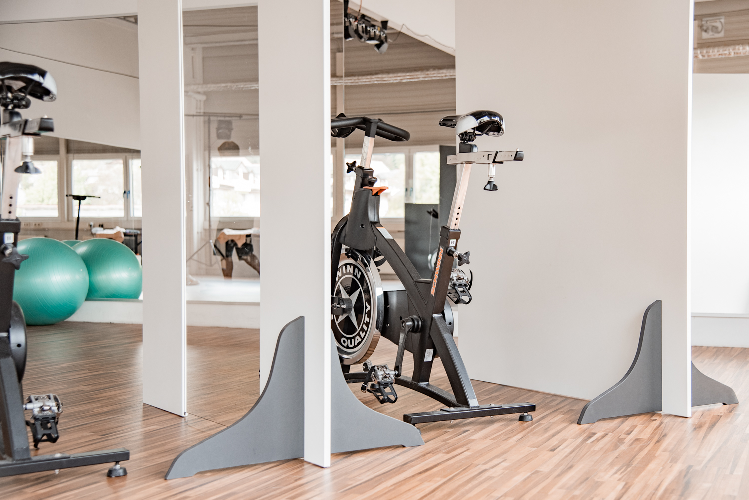 Trennwände Exclusive stehen zwischen Indoor-Cycles, im Vordergrund grüne Gymnastikbälle