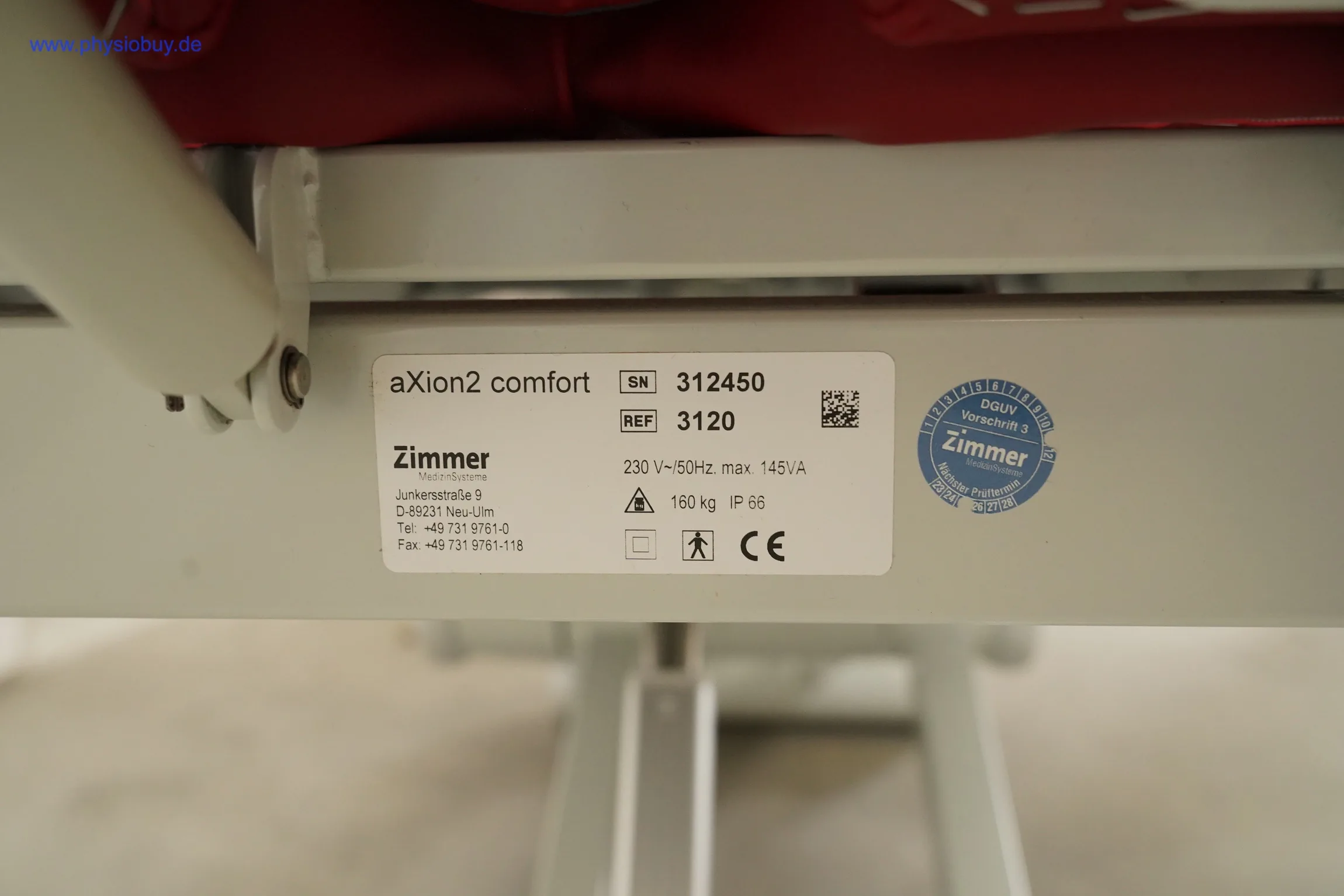 Typenschild der Zimmer Axion Behandlungsliege am Liegenrahmen mit Aufschrift aXion2 comfort und CE-Zeichen