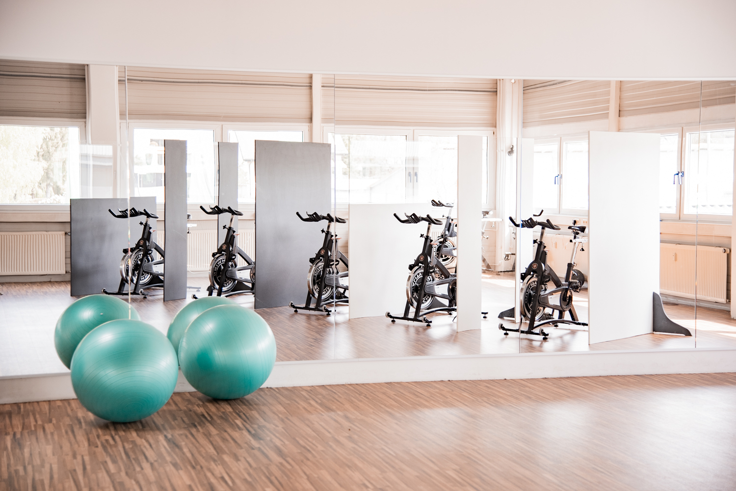 Trennwände Basic im Hintergrund einer Cycling-Reihe, im Vordergrund grüne Gymnastikbälle