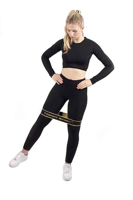 Frau führt seitliche Schritte mit einem gelben Hip-Loop-Band um die Oberschenkel aus