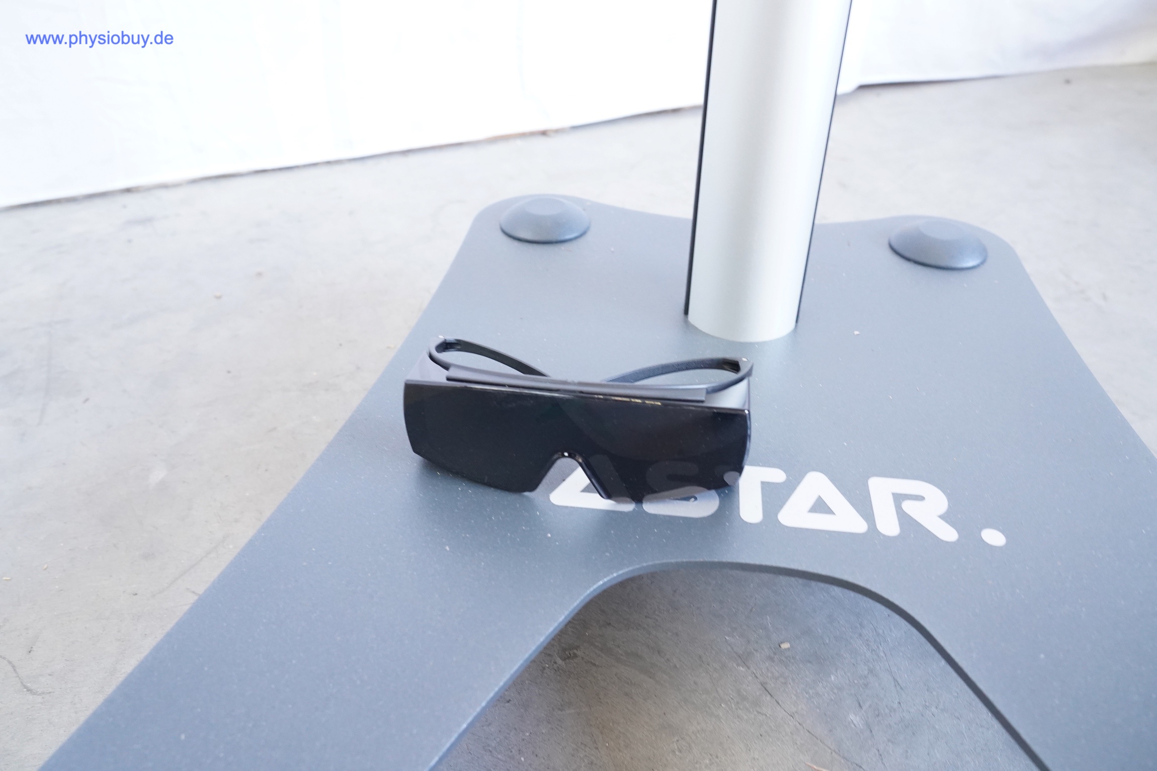 ASTAR Infrarotlichtstrahler Lumina: dunkle Schutzbrille auf der grauen Standfußplatte des Rollstativs mit ASTAR-Schriftzug
