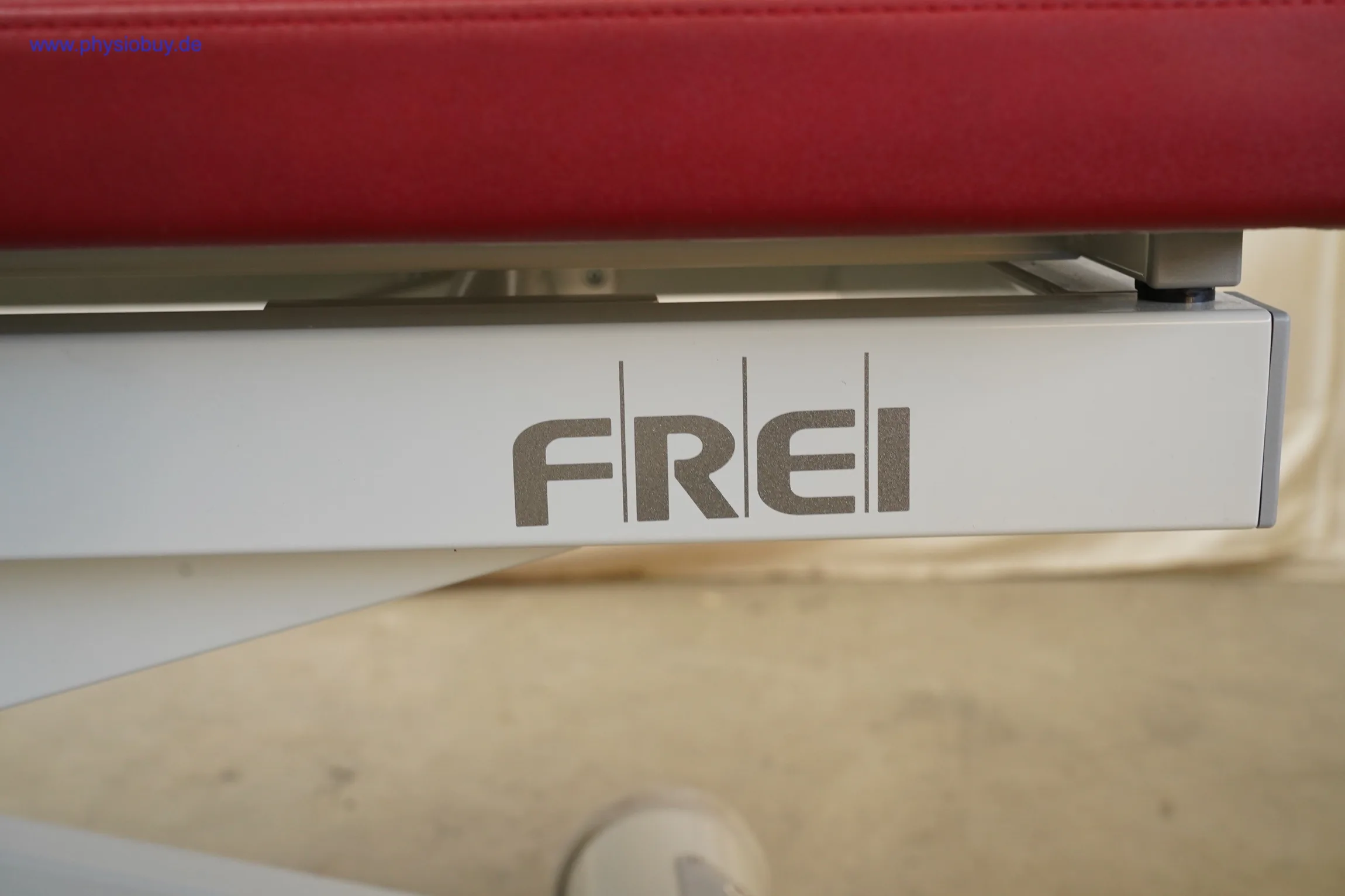 Herstellerschriftzug FREI am Gestell der roten Behandlungsliege, Nahaufnahme