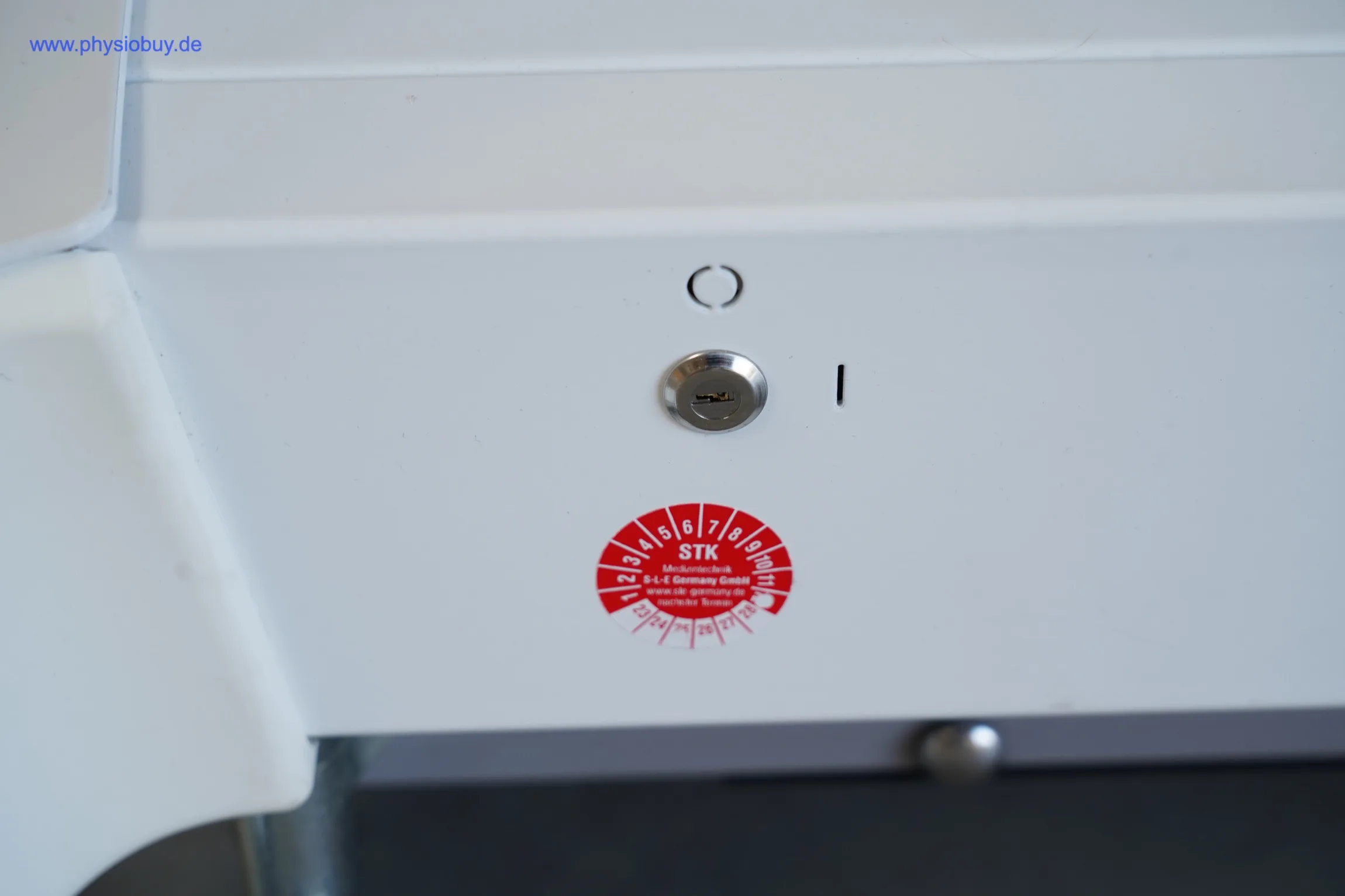 Schlüsselschalter und Prüfplakette an der Therapieliege Gymna, Nahaufnahme