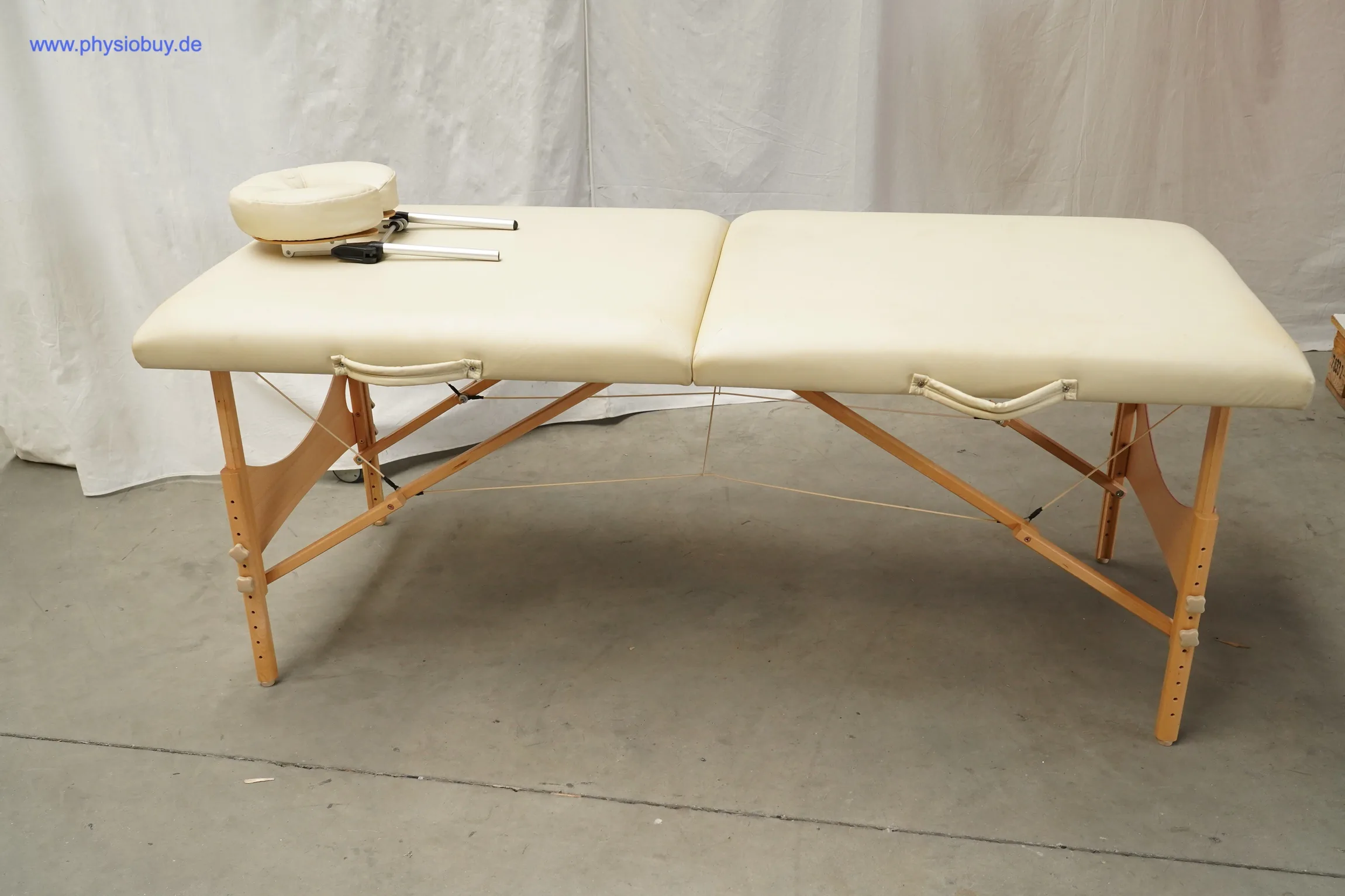Klappbare Massageliege mit hellem Polster und aufgelegter Kopfpolsterung