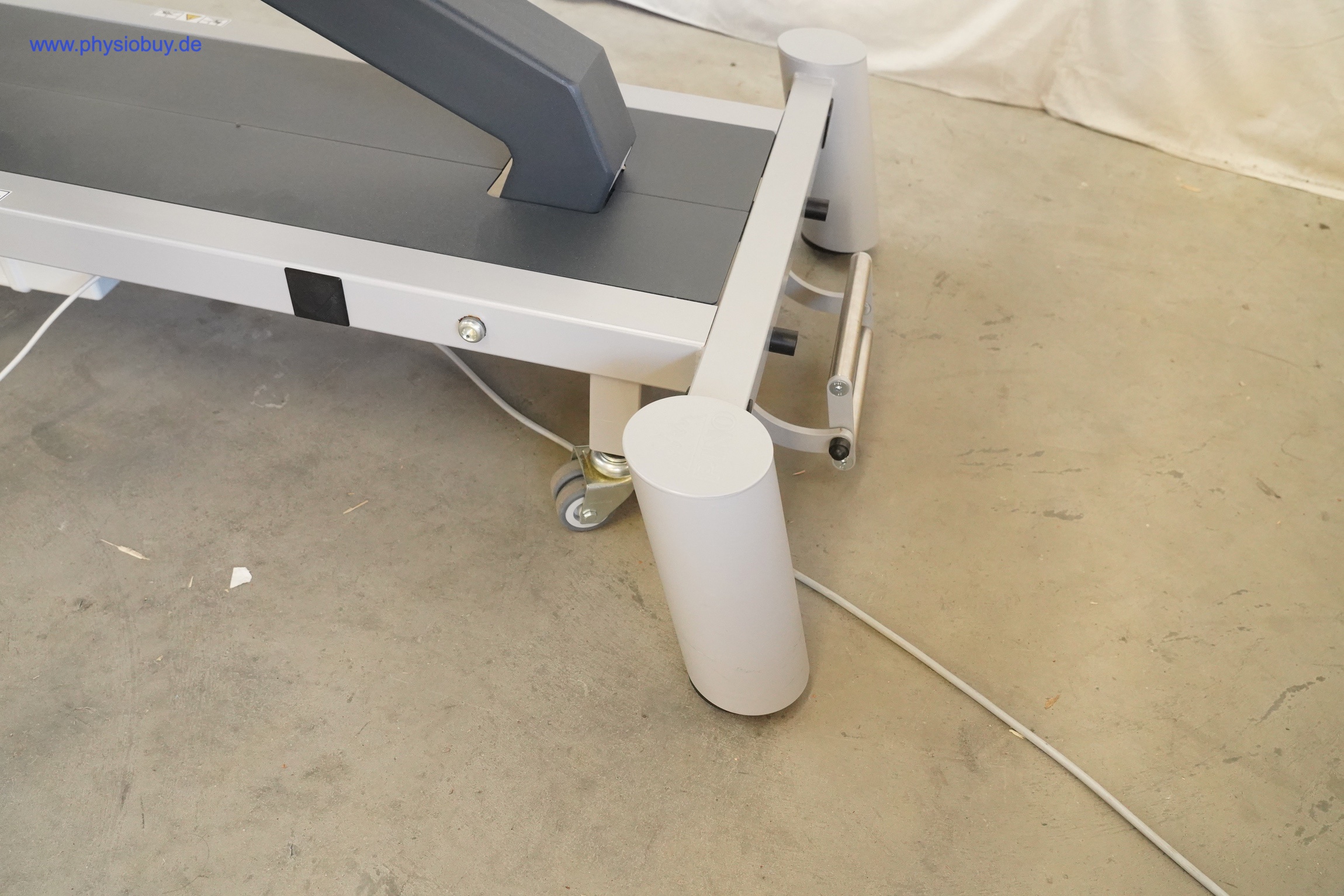 PINO XPert+ Therapieliege, Detailansicht des grauen Untergestells mit Rollen und Stoßschutz-Zylindern auf Betonboden
