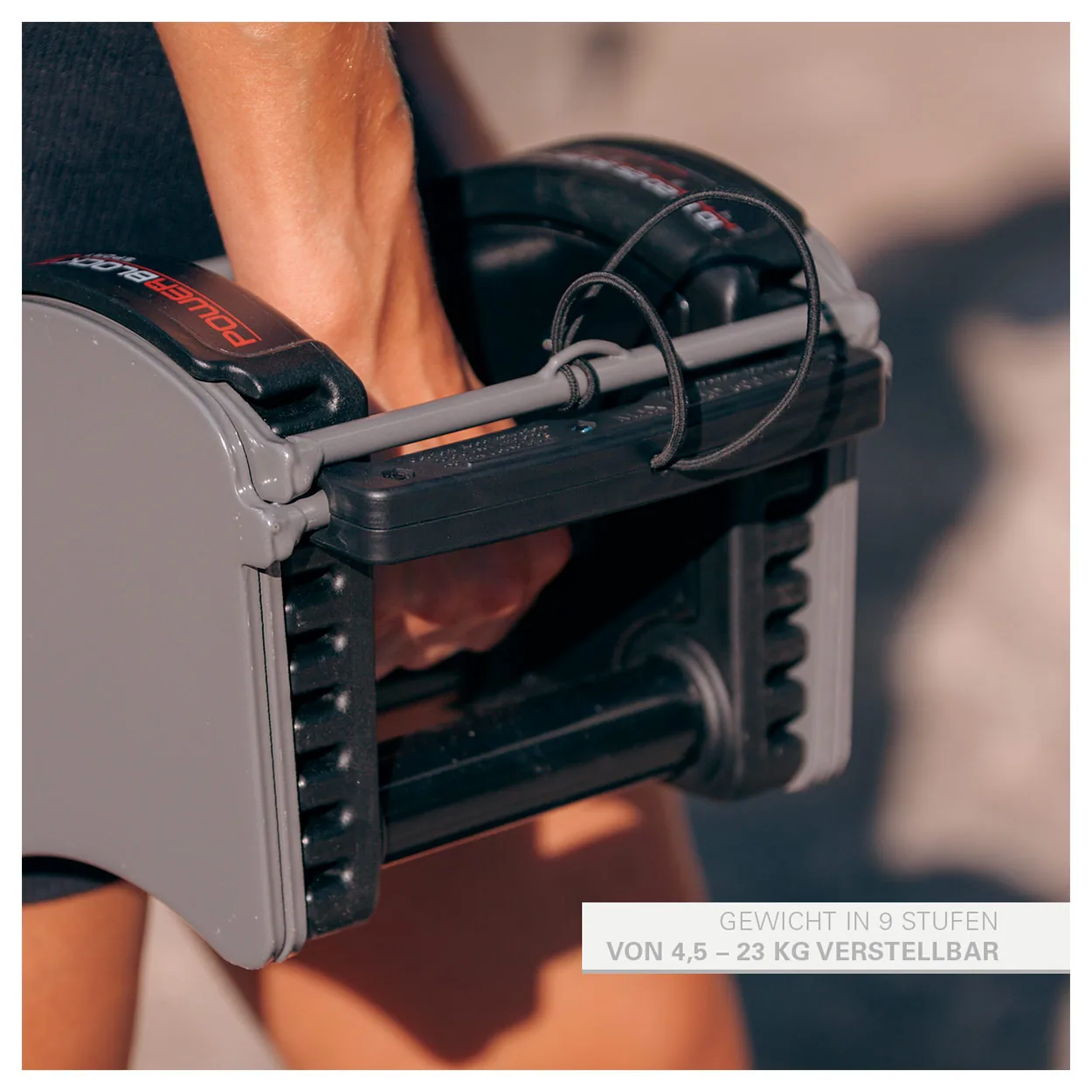 Verstellbare Kurzhantel Power Block Sport 50 im Ständer, Hand am Gewichtsstift, 9 Stufen von 4,5 bis 23 kg