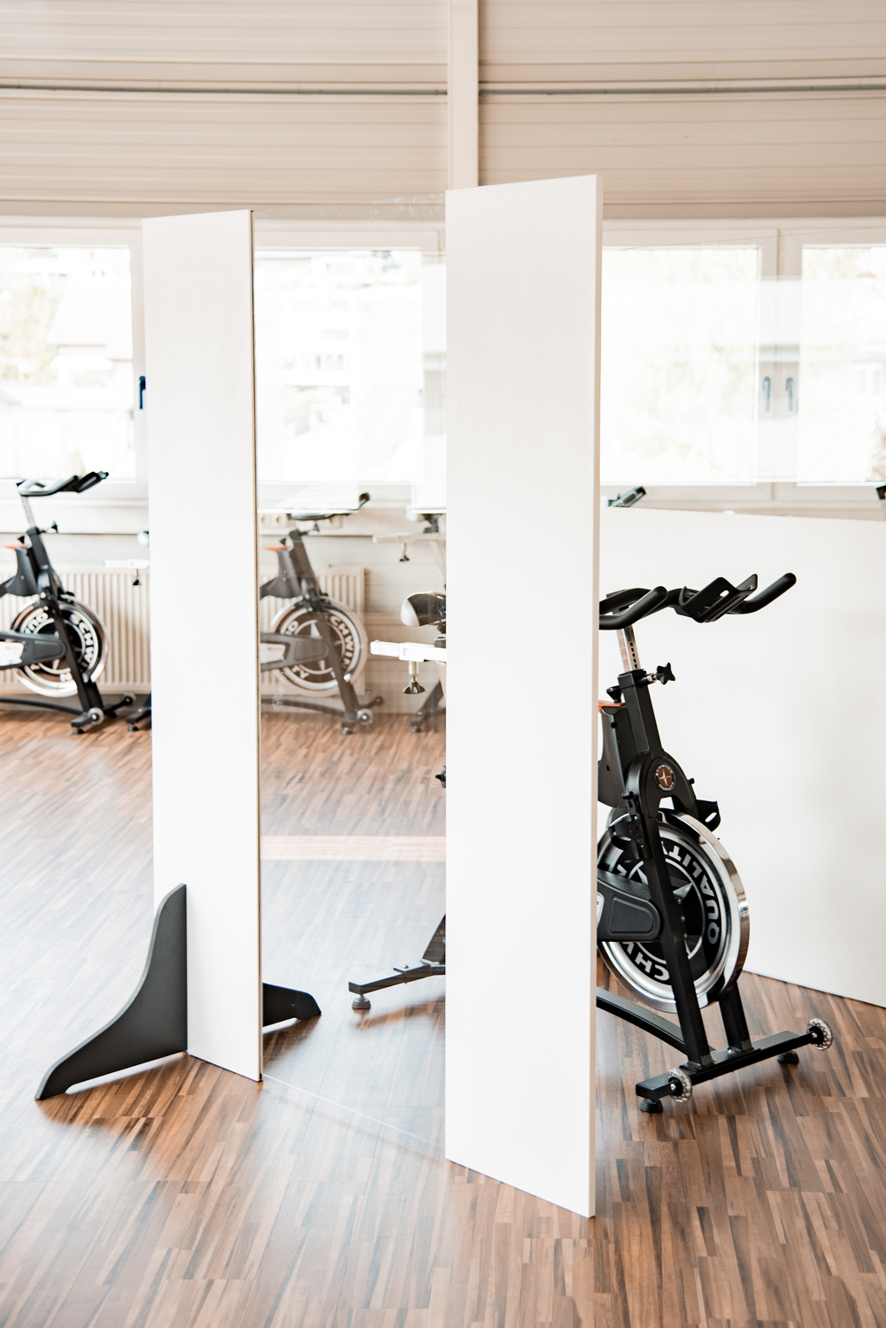 Anthrazitfarbene Trennwände Exclusive stehen zwischen Indoor-Cycles im Fitnessstudio