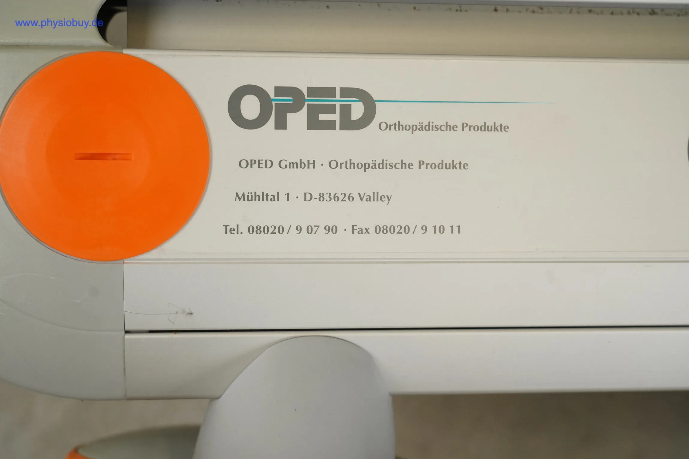 Camoped OSG Bewegungsschiene: Herstelleraufdruck von OPED mit Adresse und Telefonnummer neben einem orangefarbenen Drehknopf