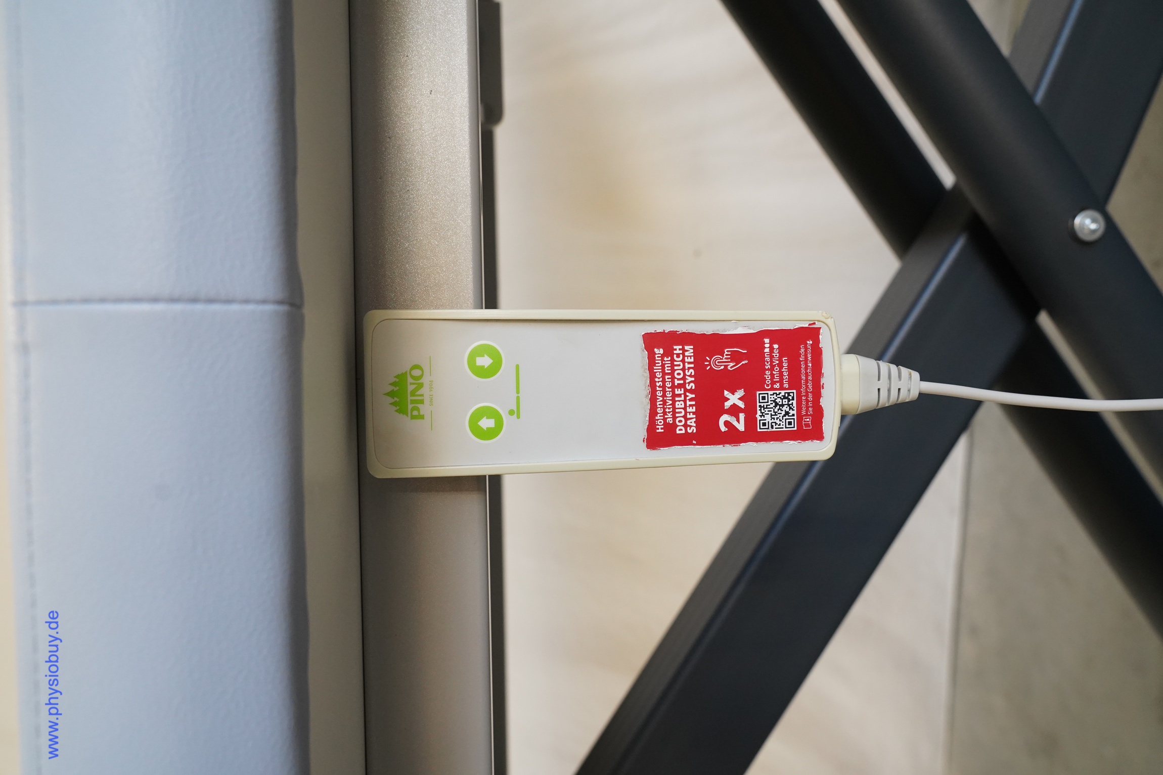 PINO XPert+ Therapieliege: Handschalter mit Pfeiltasten und rotem Double-Touch-Aufkleber unter der Polsterfläche
