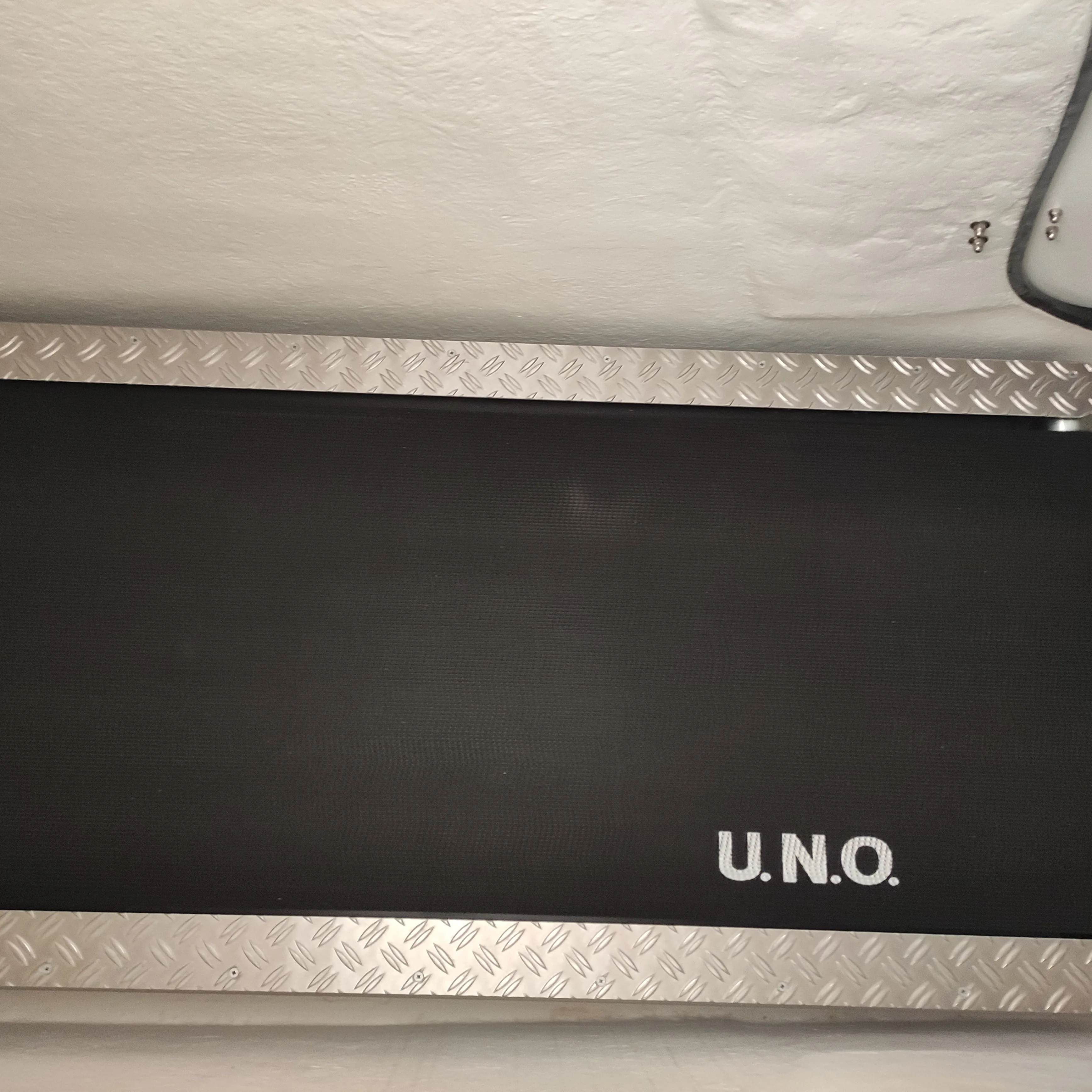 Lauffläche des VACUMOVE-Laufbands mit Markenschriftzug U.N.O. und Riffelblech-Rahmen