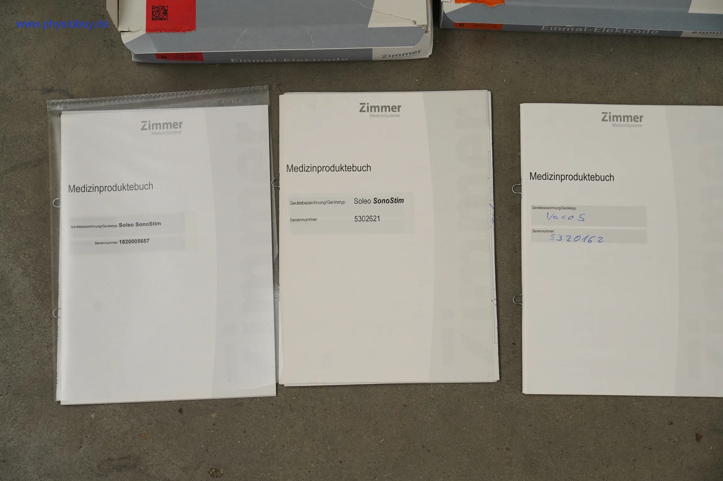 Drei Medizinproduktebücher von Zimmer zum Soleo SonoStim liegen nebeneinander auf grauem Untergrund