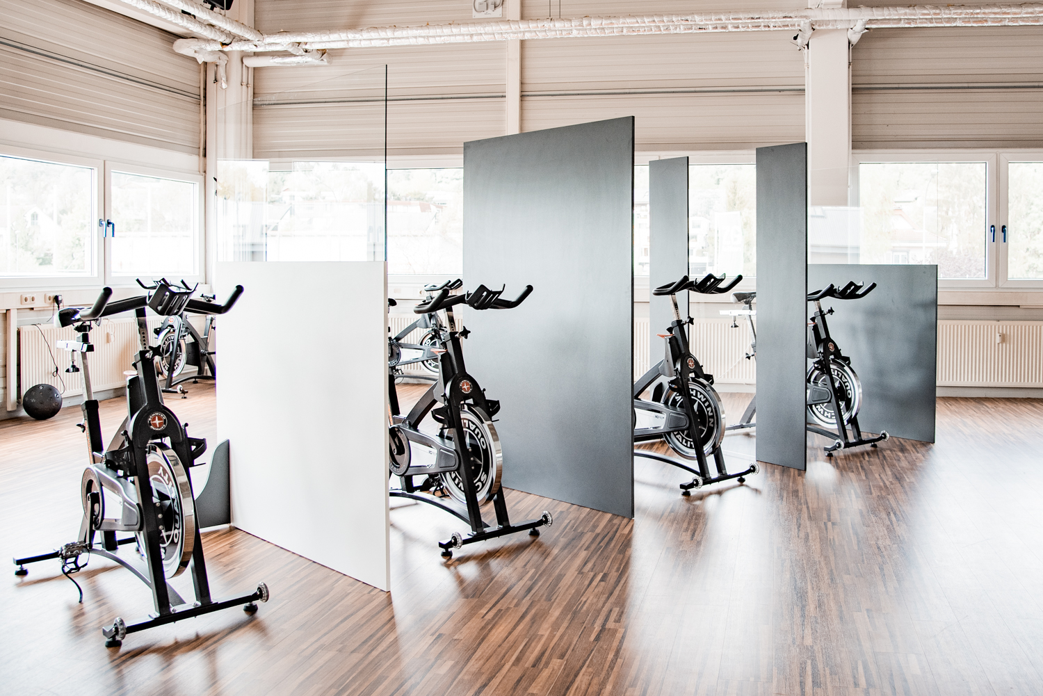 Reihe von Trennwänden Standard trennt Indoor-Cycles diagonal im lichtdurchfluteten Fitnessstudio