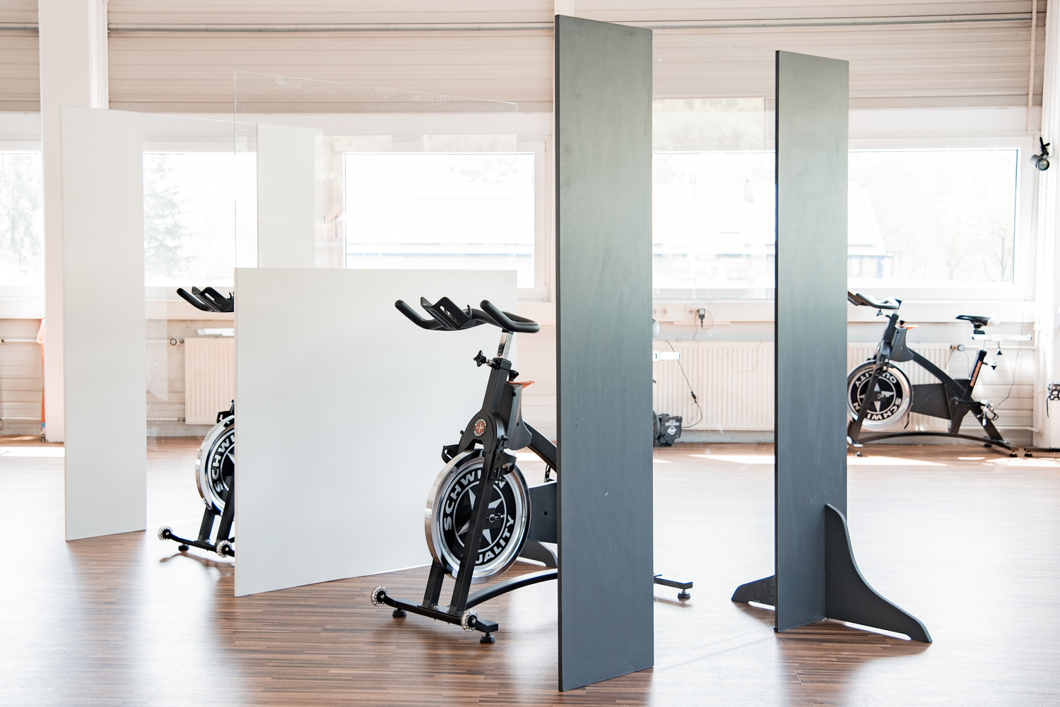Mehrere Trennwände Exclusive stehen versetzt zwischen Indoor-Cycles im Fitnessstudio
