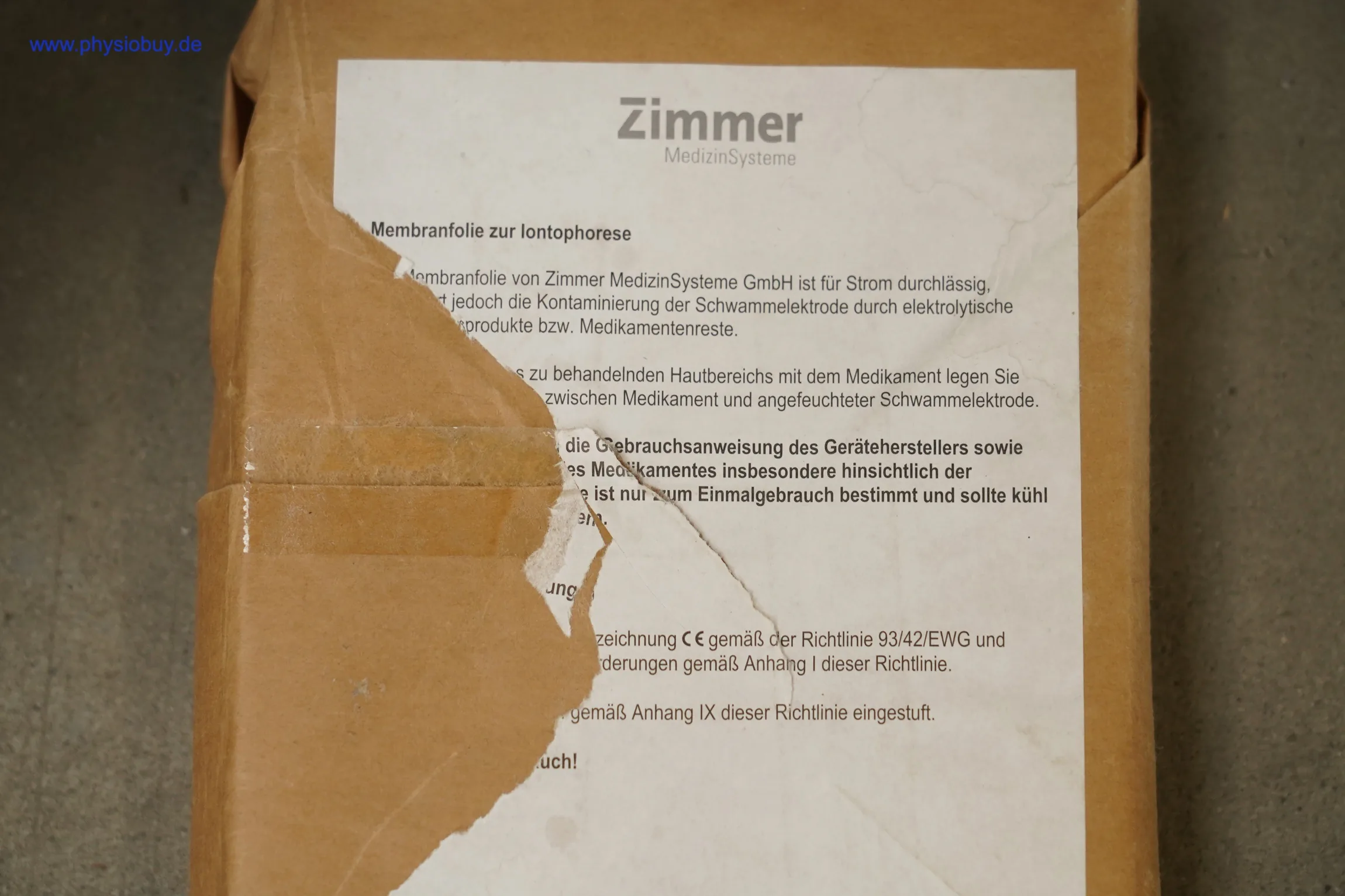 Beschädigte Kartonverpackung mit aufgeklebtem Zimmer-Etikett zu Membranfolie für Iontophorese, teils abgerissen