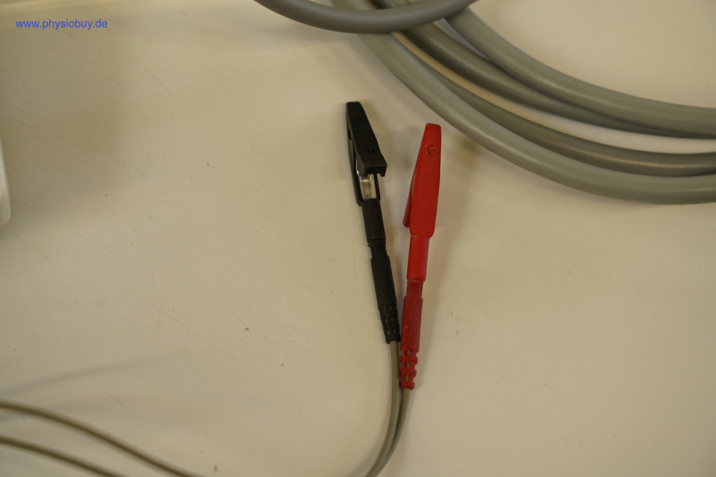 Zimmer SonoStim: Patientenkabel mit schwarzem und rotem Stecker, daneben graue Kabel auf hellem Untergrund