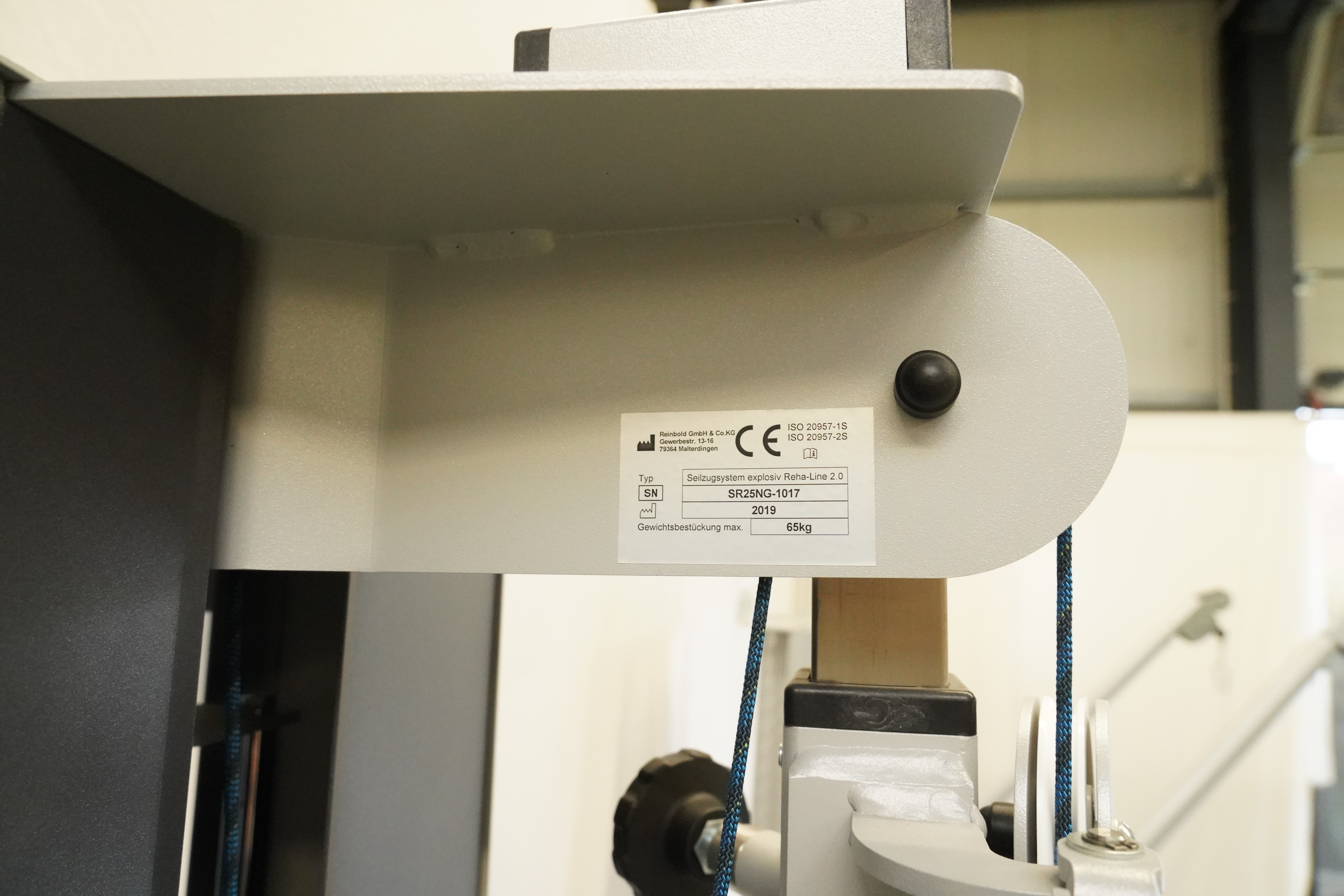 SVG RehaLine 2.0 KG-Gerätesatz: Typenschild mit CE-Kennzeichen an grauer Metallverkleidung, daneben ein blaues Seil
