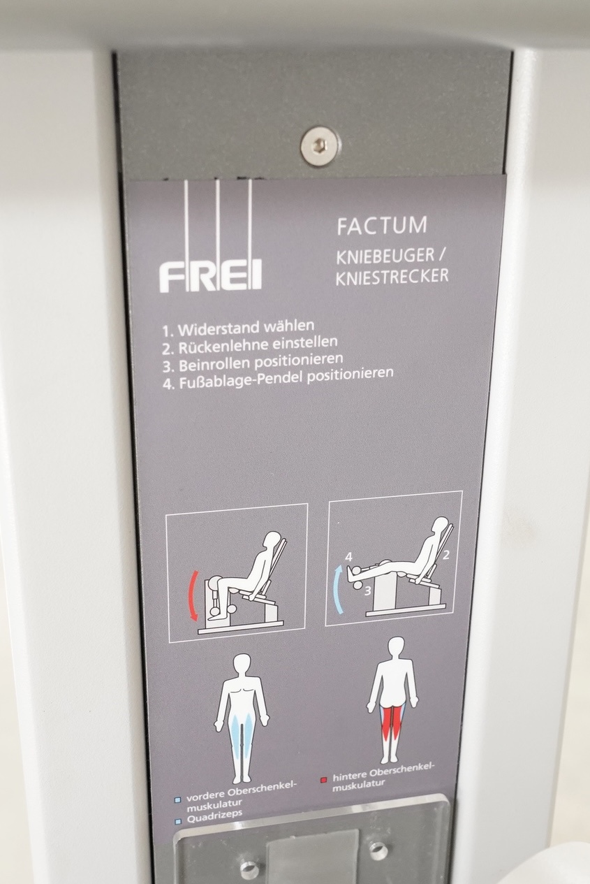 FREI Factum Novus II: Hinweisschild am Gerät mit Kniebeuger/Kniestrecker, Bedienschritten und Muskelgrafiken